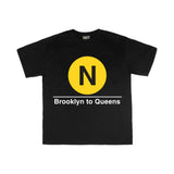 Toddler Classic Subway Logo Tee | Black t-shirt with a blue circle featuring a white "N". Text below reads: "Brooklyn to Queens." Perfect for fans of the NYC Subway Line.